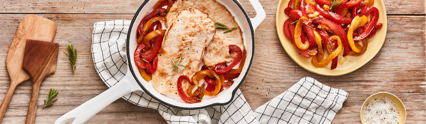 Escalopes de dinde cuitent à la poêle, accompagnées d'une poêlées de poivrons jaunes et rouges