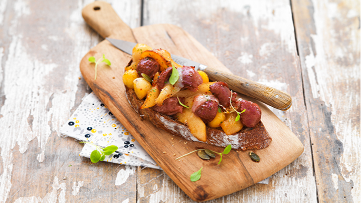 Visuel recette d'une tartine grillée aux gésiers de volaille confits, pommes et poires sur une planche apéro