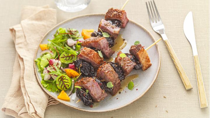 Visuel recette de brochettes de filet de canard aux pruneaux et cumin accompagnée d'une salade et de petits légumes croquants