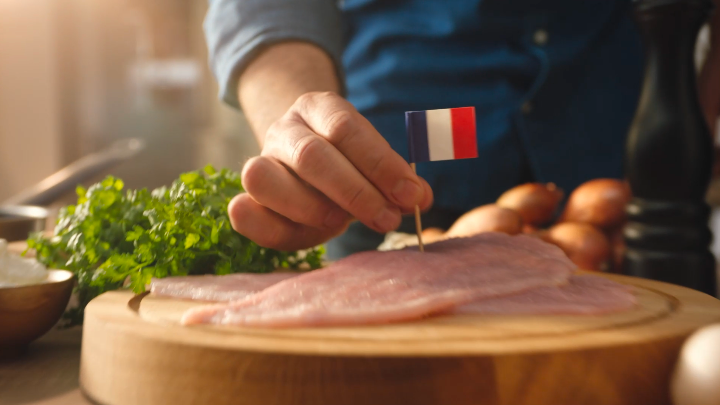 Escalope de volaille française disposée sur une planche en bois avec un pic drapeau français sur le dessus